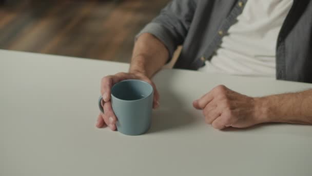 用茶杯近距离观察男性的手 老孟人的手拿着一个装有天然矿泉水的杯子 老年人的茶 喝水的好处 — 图库视频影像