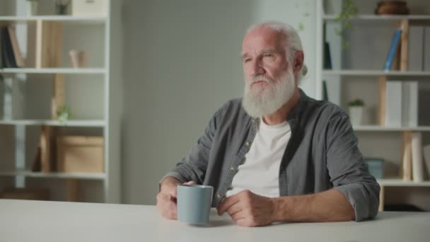 Serious Old Man Sienta Mesa Con Una Taza Café Relajado — Vídeo de stock
