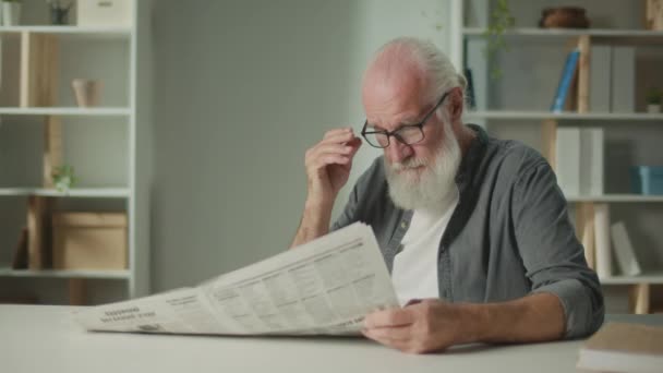 Een Serieuze Slimme Oude Man Zit Aan Een Tafel Leest — Stockvideo