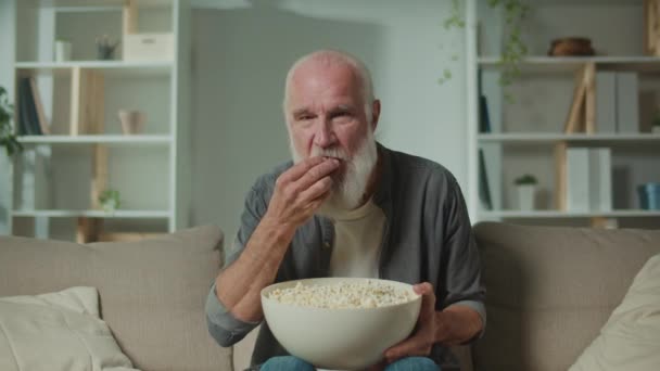 Old Man Sitting Sofa Eating Popcorn Watching Scary Movie Movie — Stock Video