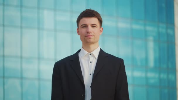 成功した若い男性エンジニアまたは建築家の肖像画 青い窓が付いている建物の近くに立って — ストック動画