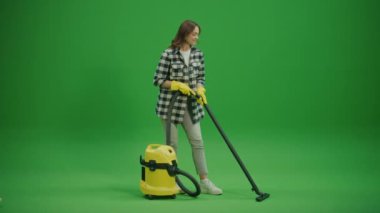 Yeşil Ekran. Sarı Plastik Eldivenli Gülümseyen Genç Bir Ev Kadını Süpürme. Akıllı Temizlik Teknolojisi. Aletlerle Çevre dostu Temizlik.
