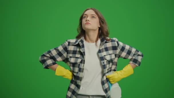 绿色屏风 一位身穿黄色手套 头戴清洁喷雾器 头戴破布的有思想的年轻女性 一位家庭主妇在想从哪里开始清洁 卫生和安全议定书 — 图库视频影像