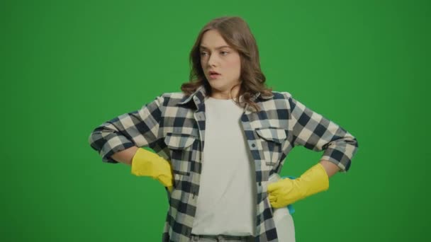 绿色屏风 一名戴黄色橡胶护目镜的严肃年轻女子 拿着清洁剂瓶和抹布检查清洁剂的用量 — 图库视频影像