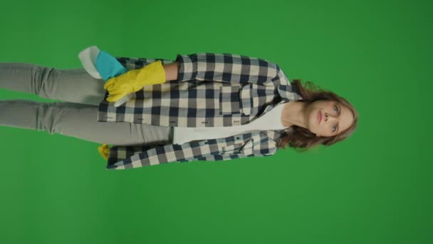 垂直视图 绿色屏幕 一名戴黄色橡胶护目镜的严肃年轻女子 拿着清洁剂瓶和抹布检查清洁剂的用量 — 图库视频影像