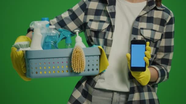 绿色屏风 女性家庭主妇手部特写 手持装有清洁用品的盒子和装有蓝色屏风的智能手机 无线及应用控制清洁装置 — 图库视频影像