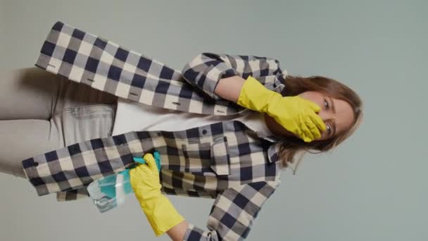 一个穿着黄色手套的年轻女人拿着一块干净的抹布 在灰蒙蒙的背景上闻到一股难闻的气味的画像 方便宠物的清洁方法 — 图库视频影像