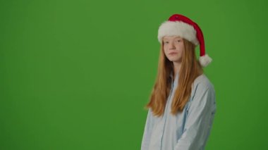 Yeşil Ekran. Noel Baba Şapkalı Kız, Noel alışverişini ve kredi kartını heyecanla gösteriyor. Bayram çılgınlığı, mevsimlik alışveriş ve Noel tatili atmosferi.