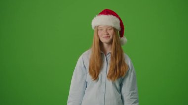Yeşil Ekran. Noel Baba Şapkalı Kız Heyecanla Noel Hediyelerini Gösteriyor. Bayram çılgınlığı, mevsimlik alışveriş ve Noel kutlamalarının atmosferi. Tatil Alışveriş Sprei