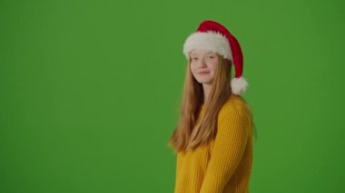Yeşil Ekran. Noel Baba Şapkalı Kız, Noel alışverişini ve kredi kartını heyecanla gösteriyor. Bayram çılgınlığı, mevsimlik alışveriş ve Noel tatili atmosferi.