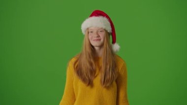 Yeşil Ekran. Noel Baba Şapkalı Kız, Noel alışveriş çantalarını neşeyle gösteriyor. Bayram ruhuna şenlikli bir bakış mevsimlik alışverişlerin ve kutlamaların heyecanını yakalıyor.