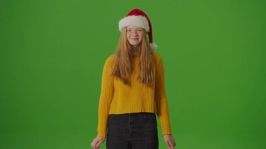Yeşil Ekran. Noel Baba Şapkalı Kız, Noel alışveriş çantalarını neşeyle gösteriyor. Bayram ruhuna şenlikli bir bakış mevsimlik alışverişlerin ve kutlamaların heyecanını yakalıyor.