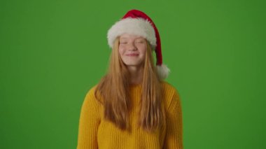 Yeşil Ekran. Noel Baba Şapkalı Kız, Noel alışveriş çantalarını neşeyle gösteriyor. Bayram ruhuna şenlikli bir bakış mevsimlik alışverişlerin ve kutlamaların heyecanını yakalıyor.