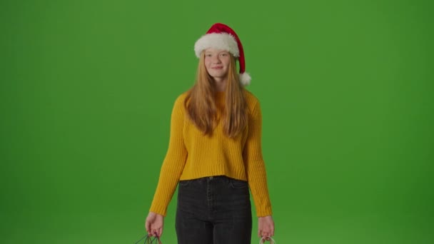 绿色屏风 圣诞老人的女儿喜形于色地展示了她的圣诞购物袋 节假日精神中的节庆轻快 抓住季节性采购和庆祝的激情 — 图库视频影像