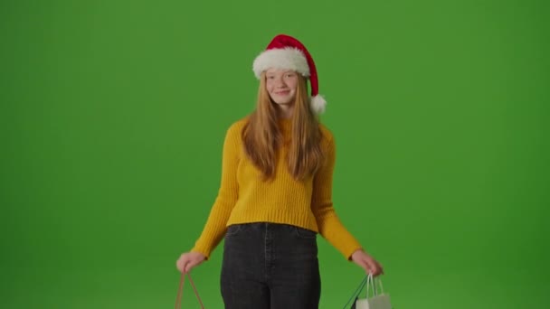 绿色屏风 圣诞老人的女儿喜形于色地展示了她的圣诞购物袋 节假日精神中的节庆轻快 抓住季节性采购和庆祝的激情 — 图库视频影像