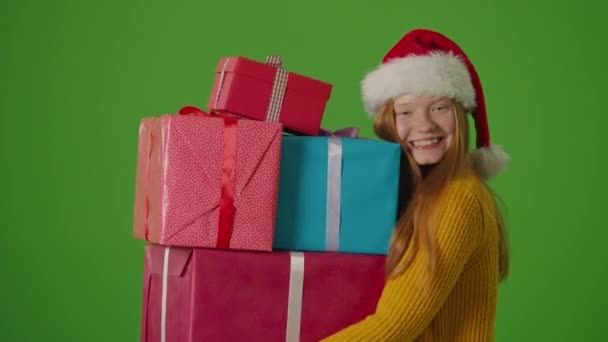 グリーン スクリーン サンタクロースの帽子で魅力的な十代の少女は笑顔を身に着け 彼女の手でギフト用の箱の弁当を保持しています お祝いの精神を体現する彼女は喜びを放射します — ストック動画
