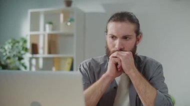 Bilek ağrısı. Bir adam laptopta çalışırken aniden bileğinde ağrı hissetti. Yaralı koluna diğer eliyle dokunuyor. Ofis sendromu konsepti. Klavye Kullanmaktan El Ağrısı.