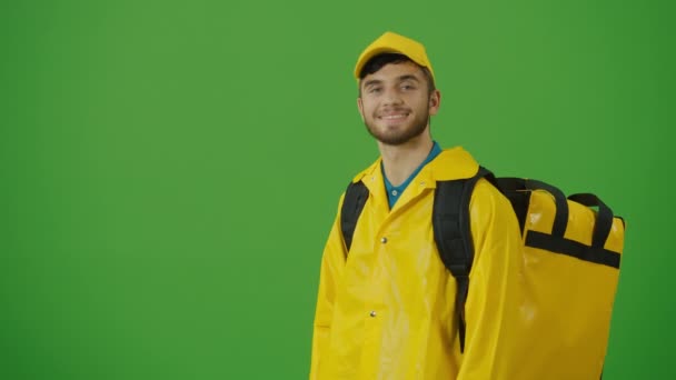 身穿黄色制服 背着热背包 用智能手机检查订货的绿色屏风青年送餐者 向客户发送订单途中的快递员 后视镜 — 图库视频影像
