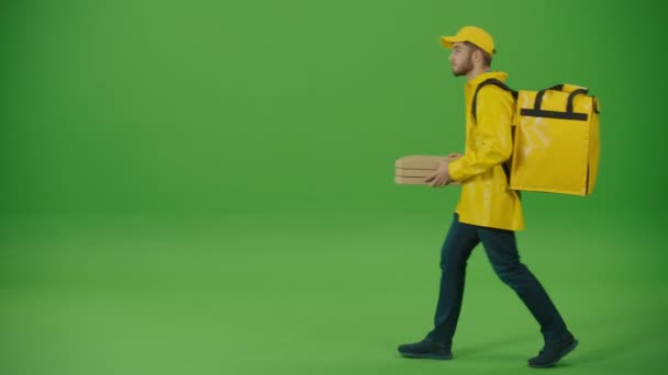 绿色屏风送货员 身穿黄色制服 背着热背包 带着披萨盒 交付工人在线交付订单客户 关于向客户发送订单的方式的信使 — 图库视频影像