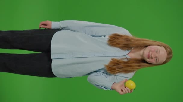 分叉绿色屏幕 垂直视频少女吃苹果时的微笑 象征着一个苹果 健康饮食和学校营养 青春在日常饮食中拥抱营养选择的生动描写 — 图库视频影像