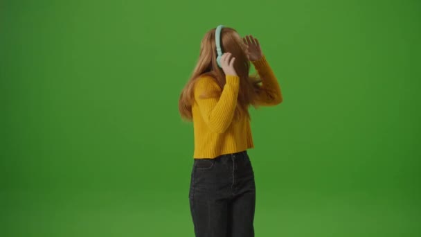 绿色屏风 迷人的少女在耳机快乐地跳舞 现代青年文化潮流 流行平台和社交网络 Instagram Stories Tiktok Dances — 图库视频影像