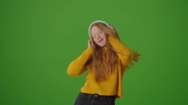 绿色屏风 迷人的少女在耳机快乐地跳舞 现代青年文化潮流 流行平台和社交网络 Instagram Stories Tiktok Dances — 图库视频影像