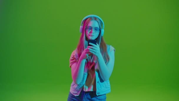 在她的手机上浏览社交媒体时 在霓虹灯下的少女 数码时代的一闪即逝 在线交流 以及网络对青少年行为的深刻影响 — 图库视频影像