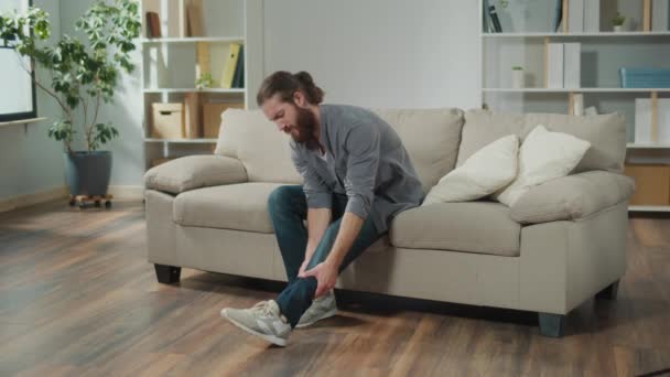 Man Has Kneecap Pain Sitting Sofa Home Feeling Illness Healthcare — Αρχείο Βίντεο