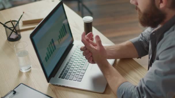 愤怒的痛苦 一个男人在笔记本电脑上工作时突然感到愤怒的疼痛 用另一只手触摸她的手 办公室综合症的概念 使用键盘造成的手痛 — 图库视频影像