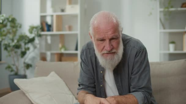 Starszy Mężczyzna Siedzący Kanapie Rozmawiający Sobą Wyglądający Zmartwionego Odzwierciedlający Chwilę — Wideo stockowe