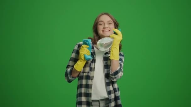 一个戴着黄色手套 面带微笑的年轻女子的画像 手里拿着一个洁净的喷雾器和一把破布 舞动着的手镯 一位女性家庭主妇正准备打扫房间 剥落的黑客 — 图库视频影像