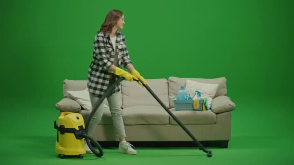 绿色屏风 一位穿着黄色橡胶护目镜 面带微笑的年轻女子坐在沙发上 对自己的清洁结果感到满意 整理及存放清洁用具 — 图库视频影像