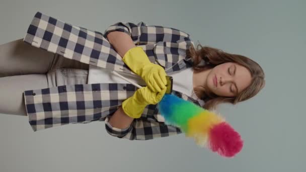 垂直ビュー 黄色い手袋の若い女性と灰色の背景に誰かとダストパンテキスト 仮想クリーニング相談 — ストック動画