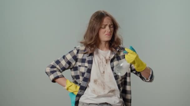 穿着黄色手套 手握清洁喷雾器和抹布 双手放在灰色背景上的年轻女性家庭主妇肮脏而烦躁 组织宠物用品和空间 — 图库视频影像