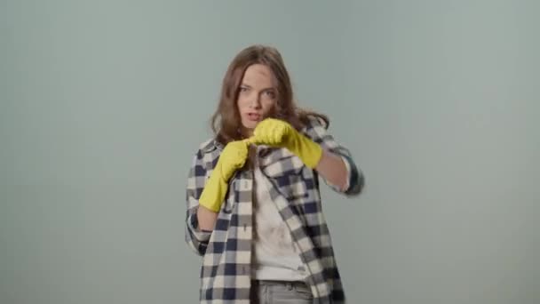 黄色い保護ゴム製手袋の汚れた深刻な若い女性の主婦は灰色の背景の土と戦います 電化製品による環境に配慮したクリーニング スピードクリーニング — ストック動画
