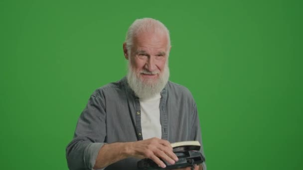 绿色屏风 一位老人的肖像展示了如何使用老式电话 一位老人证明了老式电话的便利性 并展示了高音喇叭的使用简单易行 — 图库视频影像