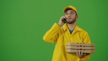 Fast Food Teslimat Adreslerini aramak için akıllı telefon kullanan yeşil ekran yiyecek dağıtıcısı. Siparişi kontrol etmek için akıllı telefonu kullanan sarı üniformalı bir teslimatçı. Hızlı teslimat.