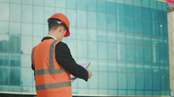 Мужчина Инженер Архитектор Шлеме Пиджаке Безопасности Смотрящий Строительные Рисунки Руке — стоковое видео