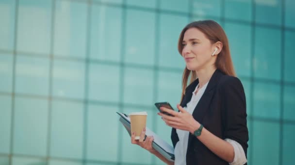 穿着西装的成功女商人的画像 走进现代玻璃商务区 拿着咖啡杯 使用智能手机 新业务 工作日 自由职业者 — 图库视频影像