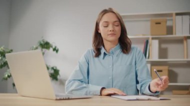 Ciddi bir genç bayan ofis çalışanı dizüstü bilgisayarla çalışırken not alır. Evden Çalışan Akıllı Kadın, Webinars ya da Sanal Eğitim Çalışma Derslerini İzliyor. Uzak Çalışma için Teknolojik Araçlar.