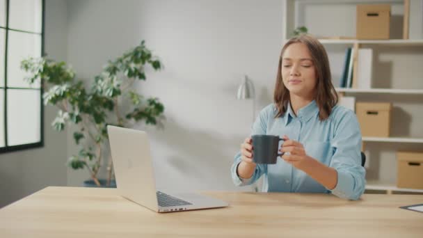 コワーキングでコーヒーブレイクをしている女性オフィスワーカーの笑顔 ラップトップで作業中に紅茶を飲むリラックスした若い女性 日常のルーチンコンセプト — ストック動画