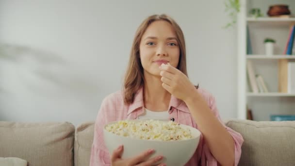 Tânără Fericită Care Stă Canapea Mănâncă Popcorn Uită Televizor Femeia — Videoclip de stoc