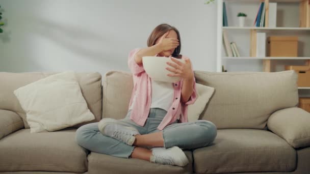 Young Woman Sitting Sofa Eating Popcorn Dan Watching Scary Movie — Stok Video