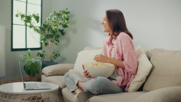 Μια Ευτυχισμένη Γυναίκα Κάθεται Στον Καναπέ Τρώει Ποπ Κορν Και — Αρχείο Βίντεο