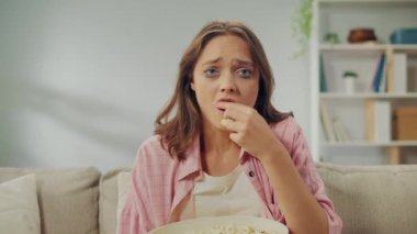 Koltukta oturan, patlamış mısır yiyen ve hüzünlü bir film izleyen genç bir kadın. Melodrama izlerken ağlayan kadın. Duygusal çıkış ve kendini ifade etmenin bir yolu olarak filmler. Sinema ve Rolü.