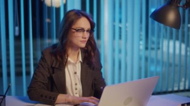 Genç Bir Kadın Ofis İşçisi Akşam Ofisinde Oturuyor, Geç Saatlere Kadar Çalışıyor ve Profesyonel Yorgunlukla Mücadele Ediyor Ve Ofis Yorgunluğu İyileşme Gereğini ve Uzun Saatlerin Gerilimini Vurguluyor