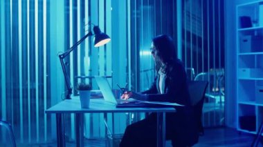 Genç Bir Kadın Ofis İşçisi Akşam Ofisinde Oturuyor, Geç Saatlere Kadar Çalışıyor ve Profesyonel Yorgunlukla Mücadele Ediyor Ve Ofis Yorgunluğu İyileşme Gereğini ve Uzun Saatlerin Gerilimini Vurguluyor
