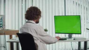 Modern Şehir Ofisinde oturan bir doktor yeşil ekranlı bir bilgisayar üzerinde çalışıyor. Yüksek kalite tıbbi hizmetler sunuyor, hızlı yaşam tarzlarına terzilik hizmeti veriyor. Sağlık hizmetleri kavramı
