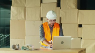 Hard Hat and Safety Yelek Mühendisi İnşaat Alanındaki bir dizüstü bilgisayarda, Verimli Proje Yönetimi için Dijital Aletleri Kullanıyor. Modern Mühendislikte Yenilik ve Teknoloji.