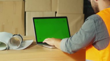 Bir Mühendis Sitedeki Proje İzleme ve Koordinasyon için Yeşil Ekran Bilgisayarı Kullanıyor. Bu Resim Modern İnşaatta Proje Yönetiminin Akıtılmasında Dijital Araçların Rolünü Vurgular.
